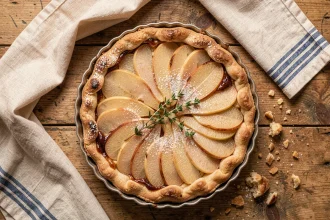 Tarte aux poires maison vue de dessus sur une table en bois rustique avec un torchon en lin vintage